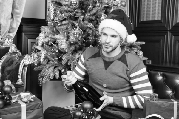 El hombre celebra la fiesta de año nuevo. Santa hombre abre la botella de champán en el árbol de Navidad. La fiesta está cerca, da una gran alegría. Tener un nuevo año simplemente hermoso — Foto de Stock