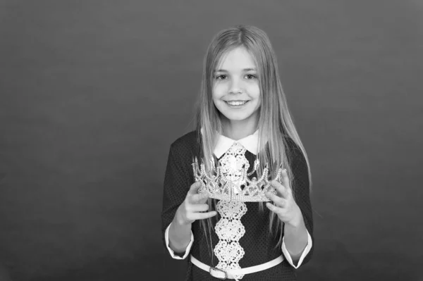 Lady princesinha. Menina bonito sorriso segurar coroa enquanto stand fundo vermelho. O melhor prémio para mim. Kid hold símbolo coroa de ouro da princesa. Feliz conceito de infância. Cada menina sonhando se tornar princesa — Fotografia de Stock