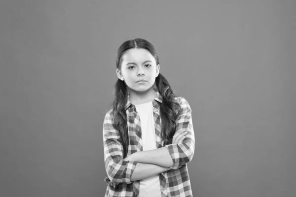 O que devo fazer? Dia das crianças. memória da infância. menina laranja fundo. moda infantil. menina da escola séria. uniforme de trabalhador. Cabelo comprido. menina pequena camisa xadrez. criança triste — Fotografia de Stock