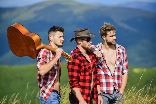 Long route. Adventurers squad. Tourists hiking concept. Hiking with friends. Men with guitar hiking on sunny day. Group of young people in checkered shirts walking together on top of mountain