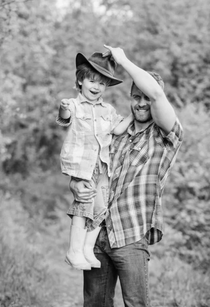 Fin de semana en la granja. Niño y padre en el fondo de la naturaleza. Espíritu de aventuras. Pequeño ayudante en el jardín. Niño divirtiéndose papá vaquero. Familia de granja. Vacaciones en la granja de padres. Creciendo lindo vaquero — Foto de Stock