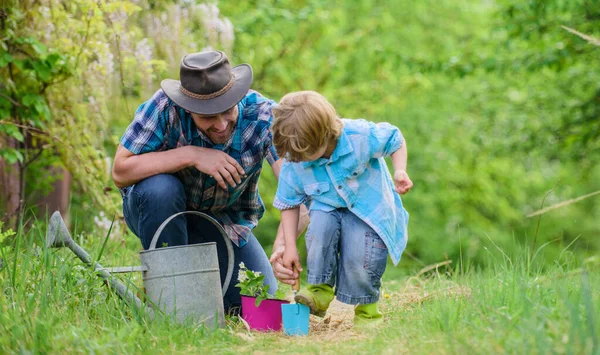 Little helper in garden. Planting flowers. Make planet greener. Growing plants. Take care of plants. Boy and father in nature with watering can. Gardening tools. Dad teaching little son care plants — Stock Photo, Image