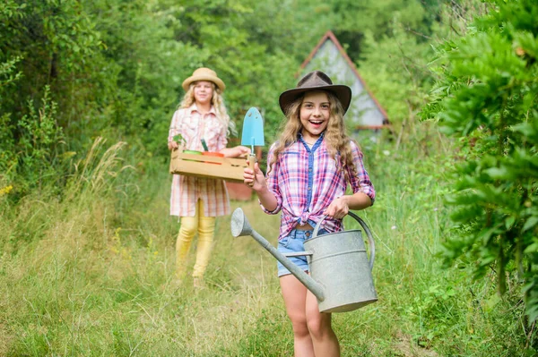 Gardeners at work. child hold gardening tools. small girl farmer with shovel and watering can. happy farming. spring country side. selective focus. ecology protection. earth day. summer farm