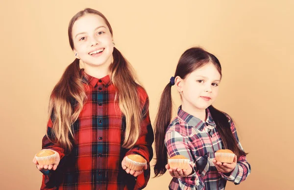 Hemlagad mat. Diet hälsosam kost och kalorier. Smaskiga muffins. Flickor söta barn äter muffins eller cupcake. Söt dessert. Kulinariska recept. Välsmakande mellanmål. Matlagning skicklighet. Systrar håller bakade muffins — Stockfoto