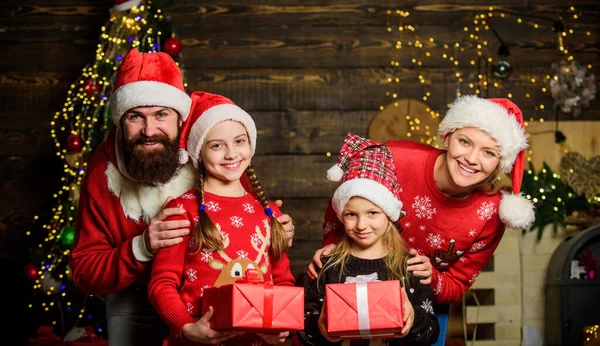 Boxing day. Happy holidays. Father bearded man and mother with cute daughters christmas tree background. Spend time with your family. Parents and children opening christmas gifts. Christmas tradition