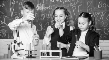 Okul laboratuvarı. Grup okulu öğrencileri Kimyasal sıvılar üzerinde çalışmadır. Kız ve çocuk öğrencisi sıvılarla okul deneyi yaparlar. Okul kimya dersi. Maddeler ile test tüpleri. Resmi eğitim