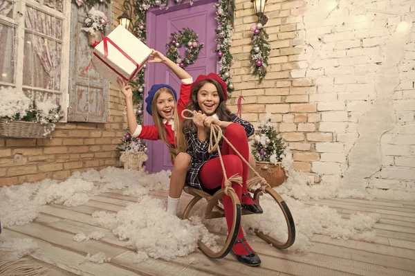 Entrega regalos de Navidad. Hermanitas felices celebran las vacaciones de invierno. La época de Navidad. Feliz año nuevo. Niña linda con regalo de Navidad. Vacaciones familiares. actividad invernal en trineo — Foto de Stock