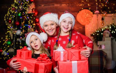 Mutlu aile kavramı. Harika yılbaşı anları. Kusursuz bir noel günü geçir. Bir sürü hediye kutusu olan küçük kızlar. Anneler için Noel sabahı rutini. Annem Noel ağacının yanında kızları kucaklıyor.