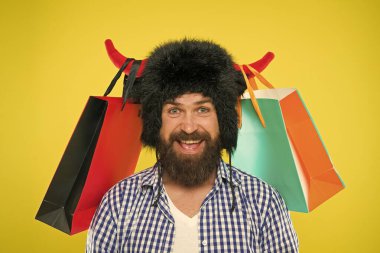 Wild about shopping. Full packages of items. Man strict face wear hat of bull with horns. Hipster shopping addicted or shopaholic. Shopping concept. Guy shopping sales season with discounts clipart