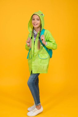 O harika biri. Mutlu küçük çocuk sarı arka planda moda yağmurluğu giyiyor. Sonbahar bakışlarıyla gülümseyen küçük bir çocuk. Küçük kız yağmurlu yolculuğa hazır. Yeşil yağmurluklarla gülümseyen sevimli küçük çocuk.