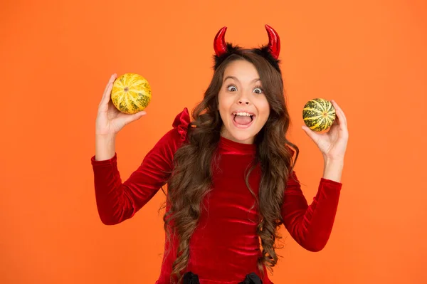 Divirtiéndose. Decoraciones para vacaciones. Imp juguetón. Chica con cuernos jugar con calabazas. Felices fiestas. Lindo niño celebrar Halloween. Vacaciones de otoño. Calabazas atributo tradicional de vacaciones de otoño — Foto de Stock