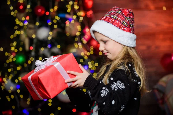 Flicka söt barn hålla insvept gåva nära julgran. Vintershopping. Helgfest som faktiskt låter kul. God jul, då. Grabben förtjusande bära tomte hatt fira jul. Köp julklapp — Stockfoto