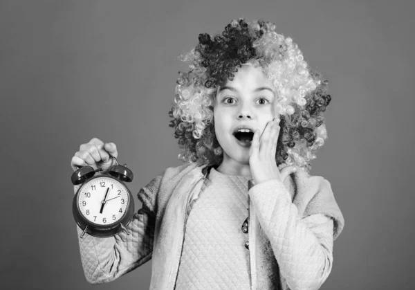 Niño colorido peluca rizada payaso estilo mantenga despertador. No estoy bromeando sobre disciplina. Falsa alarma. Las chicas se preocupan por el tiempo. Es hora de divertirse. Disciplina y concepto de tiempo. Tiempo de funcionamiento del circo —  Fotos de Stock