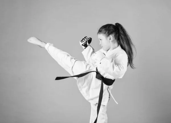 Karate gives feeling of confidence. Strong and confident kid. She is dangerous. Girl little child in white kimono with belt. Karate fighter ready to fight. Karate sport concept. Self defence skills — Stock Photo, Image
