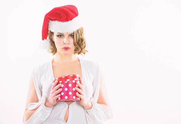 女人迷人的女士穿性感的礼服和圣诞老人的帽子。女孩举行盒打开圣诞礼物。女孩庆祝圣诞节。性感的惊喜。女孩戴圣诞老人的帽子。她有礼物给你。来自圣诞老人的礼物 — 图库照片