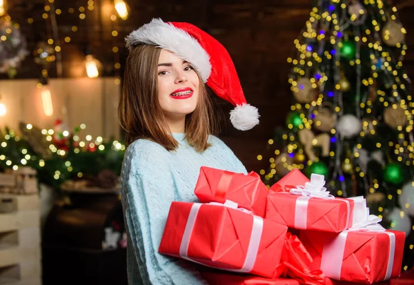 Cozy christmas atmosphere. Lady santa celebrate christmas at home. Woman santa claus hat on christmas eve. Girl stylish makeup red lips hold many christmas gifts. Bring magic into someone elses life