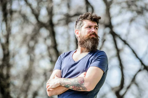 Man attractive bearded hipster posing outdoors. Confident posture of handsome man. Guy masculine appearance with long beard. Barber concept. Beard grooming. Beard care. Masculinity and manliness