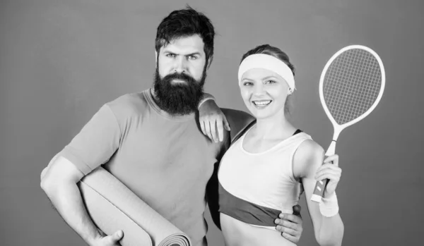 Allenati bene, vinci facilmente. Donna felice e uomo barbuto allenamento in palestra. Allenamento sportivo di coppia con tappeto fitness e racchetta da tennis. Successo atletico. Attrezzature sportive. Muscoli e corpo forti. Allena e vinci — Foto Stock