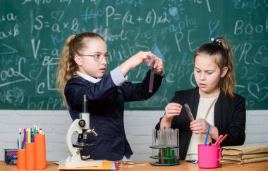 Gözbebekleri tatlı kızlar sıvı içeren test tüpleri kullanırlar. Kimyasal deney konsepti. Güvenli kimyasal reaksiyon sağlamak için güvenlik önlemleri. Dahi çocuklar kendi kimyasal teorileri üzerinde çalışırlar. Kimyanın temel bilgisi