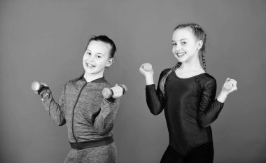 Daha güçlü bir vücuda doğru gidiyor. Dambıllarla egzersiz eden kızlar. Acemi halter egzersizleri. Çocuklar haltermavi arka plan tutun. Gençler için spor. Halterile kolay egzersizler. Sportif yetiştirme