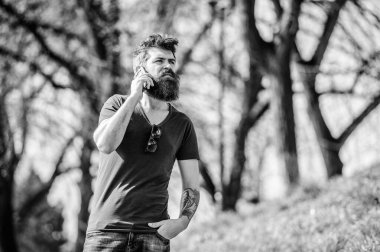 Sakallı adam cep telefonunu arıyor. İletişim konsepti. Sonra ara. Yönlendirilmiş arama. Mesajı dinliyorum. Şu anda müsait değil. Cep telefonu kullanan sakallı bir hippi. Sakallı adam arıyor.