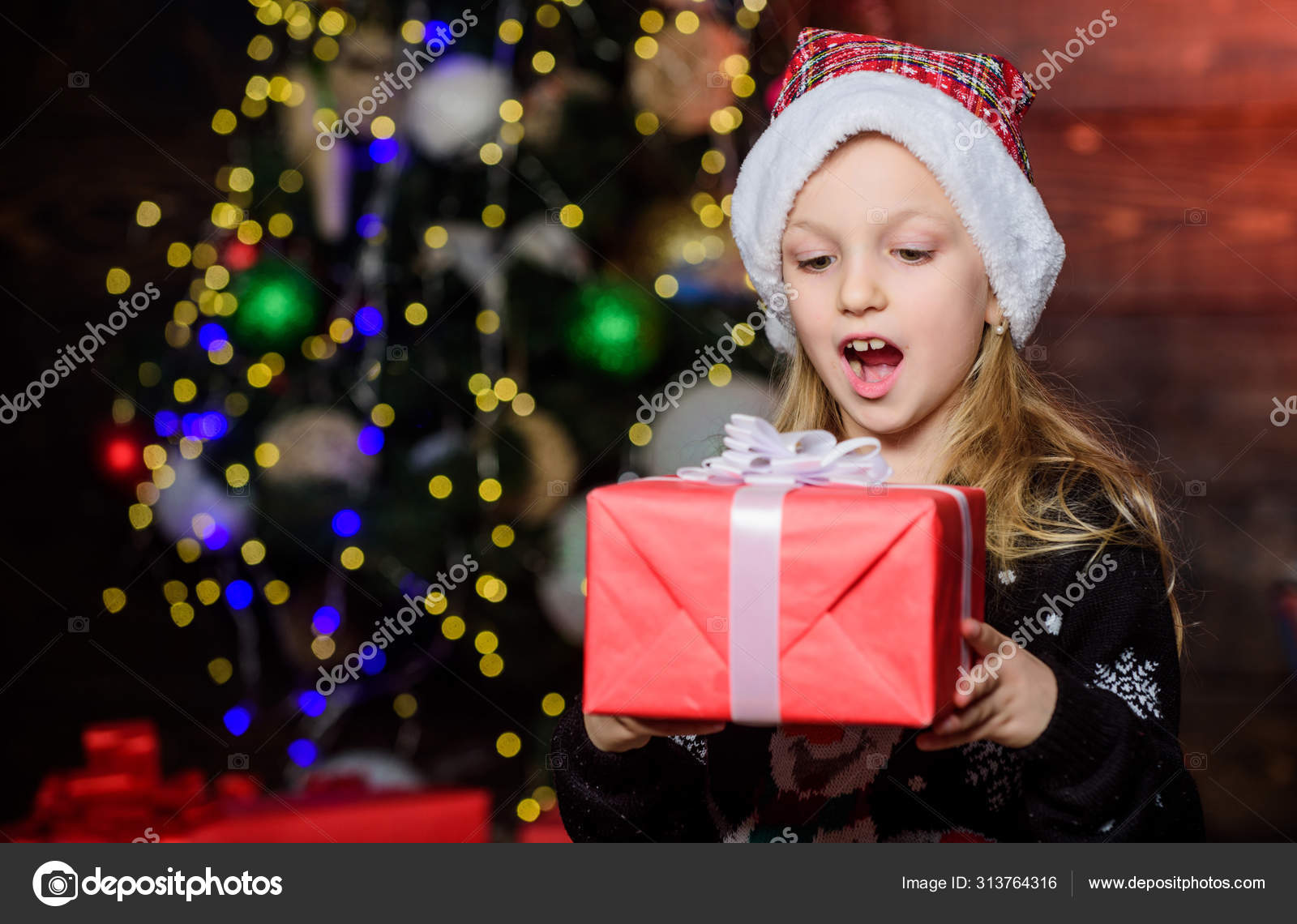 Best surprise gift ever. Adorable kid looking at gift box with surprise. Small girl keeping