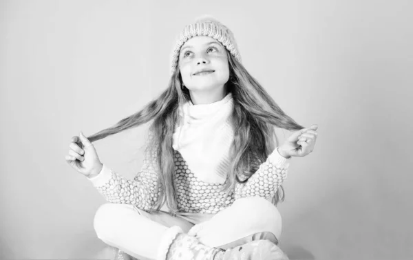 冬季时尚理念。女孩长头发放松粉红色的背景。孩子微笑时尚模特。小女孩穿可爱的针织时髦的帽子和舒适的舒适的衣服。儿童冬季时尚 — 图库照片