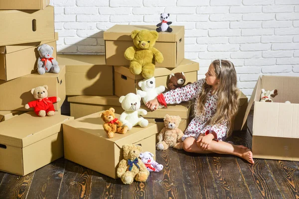 Playing into new home. new apartment. Cardboard boxes - moving to new house. happy little girl with toy. purchase of new habitation. happy child cardboard box. Hot location — Stock Photo, Image