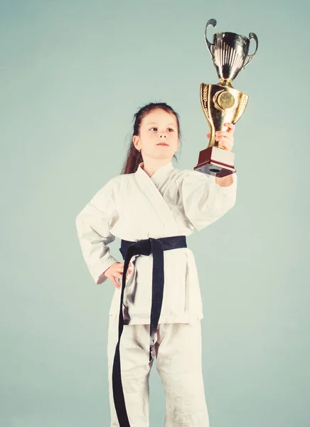 Celebrate achievement. Karate gives feeling of confidence. Strong and confident kid. Girl little child in white kimono with belt. Karate fighter child. Karate sport concept. Self defence skills