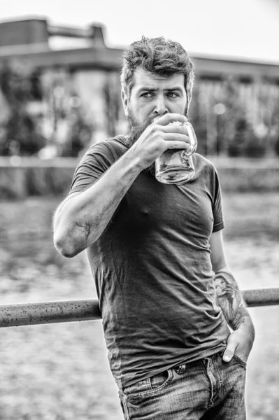 Guy having rest with cold draught beer. Hipster relaxed drinking beer outdoor. Cafe summer terrace. Light ales or dark stouts drink them all. Man with beard and mustache hold beer glass outdoors