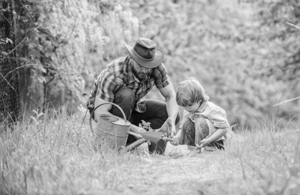 Boldog föld nap. Családi fa nursering. öntözés, pot és kapa. Kerti felszerelések. Öko-farm. kisfiú gyermeke segít apja a gazdálkodásban. apja és fia cowboy kalapban a tanyán. Föld-nap koncepció — Stock Fotó