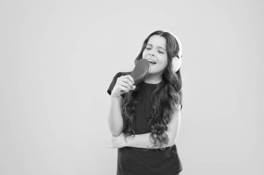 Kalbinde bir şarkı tut. Sevimli şarkı şarkıcısı. Sevimli küçük çocuk sarı arka planda şarkı vokal yapıyor. Küçük kız kulaklık çalarken şarkı söylüyor