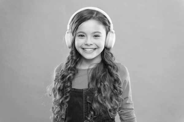 Moderno y elegante. Niño feliz disfrutando de la música moderna sobre fondo azul. Niña en auriculares elegantes escuchando canciones modernas. Uso de la tecnología moderna para el placer y el estudio —  Fotos de Stock