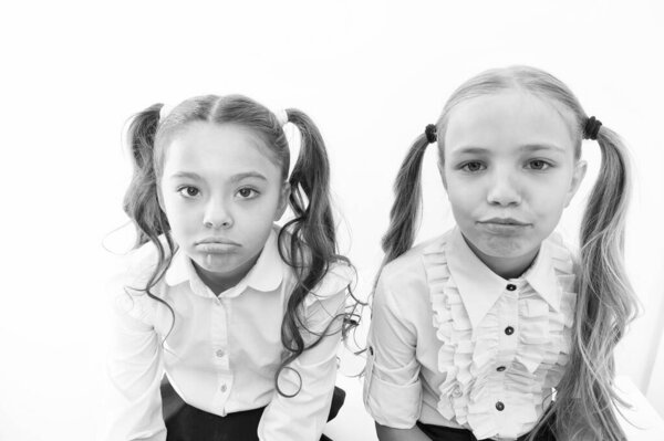 Unhappy cuties. Unhappy little schoolchildren isolated on white. Adorable small girls with unhappy emotions looking in camera. Unhappy because of school starts