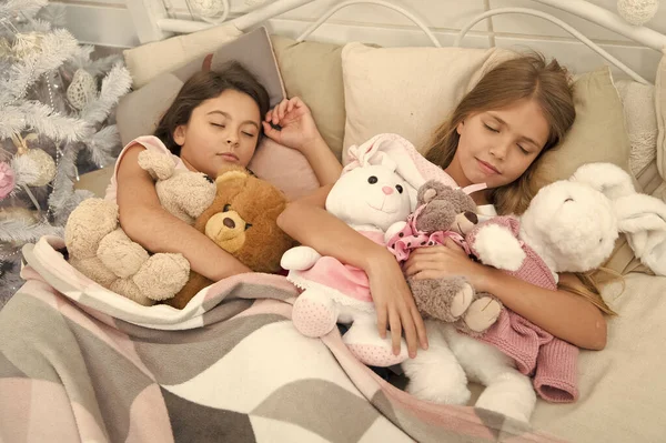 Resting on winter holidays. Sleeping children. Little children sleep at Christmas tree. Little girls lying in bed with toys. Cute girls fell asleep after Christmas night. Sleeping cuties — Stock Photo, Image