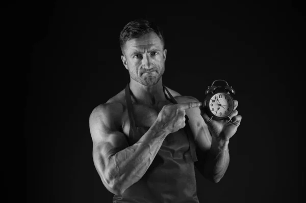 Hora de la clase magistral. Master cocinero punto en la esfera del reloj sobre fondo negro. Master chef usar delantal de cocinero en el torso muscular. Toma tiempo dominar tus habilidades. —  Fotos de Stock