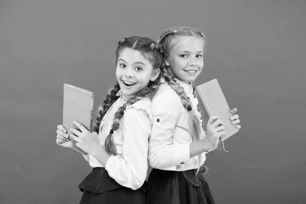 Ces livres sont absolument géniaux. Des petits enfants géniaux souriant sur fond rouge. Filles de génie heureux ou des enfants émerveillés avec des livres. Petites écolières tenant des livres avec des idées de génie — Photo