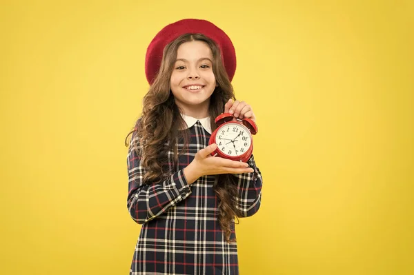 El tiempo lo es todo. Niño pequeño y feliz mostrando el momento adecuado en el fondo amarillo. Niña sonriendo y sosteniendo el despertador con señal de tiempo. Su momento es perfecto. — Foto de Stock