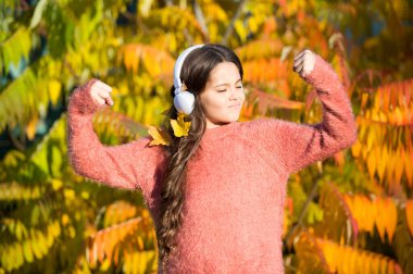 Titreşimi hisset. Sonbahar havası için müzik. Dinleme şarkısı. Sonbahar gününün tadını çıkar. Sesi dinlemenin en iyi yolu çocuğun kelime dağarcığını geliştirmesine yardımcı olmaktır. Ağacın yanındaki kulaklıklı çocuk. Güzel şarkılarla sonbahar yürüyüşleri