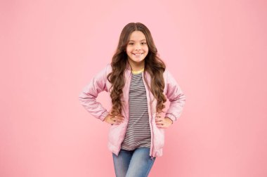 Şirin ve şık. Pembe arka planda mutlu kız gülüşü. Uzun dalgalı saçları olan esmer bir kız. Küçük şirin bir moda kızı. Güzel görünümlü küçük kız.
