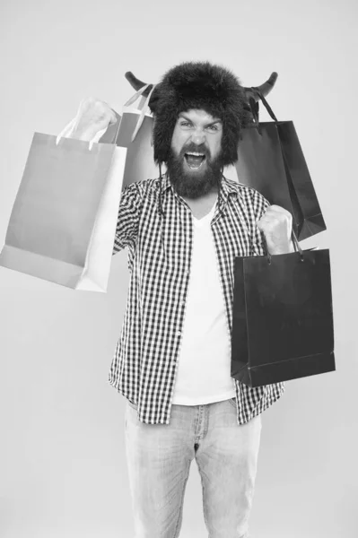 Campeón de compras. Feliz hipster con cuernos de toro sombrero sosteniendo bolsas de papel después de las compras exitosas. Hombre barbudo sonriendo con bolsas de compras. Compras es su adicción . — Foto de Stock