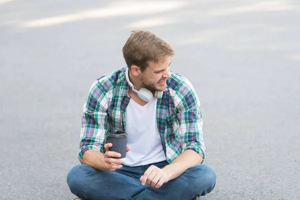 Good morning coffee. student relax and recharge. coffee to go. guy drink coffee outdoor. man sit on ground. student in headset. online education. listen music. ebook concept. man checkered shirt
