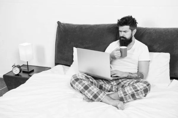 Acabo de despertarme y ya estoy trabajando. Hipster barbudo chico pijama trabajador independiente. Concepto de trabajo remoto. Redes sociales adicción a Internet. Compras en línea. Hombre navegar por Internet o trabajar en línea —  Fotos de Stock