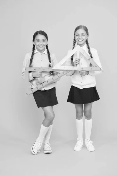 Move from theory to practice. Excellent pupils. Secondary school. Schoolgirls tidy appearance school uniform hold big rulers for geometry school lesson. Kids cute students study math. Knowledge day — Stock Photo, Image