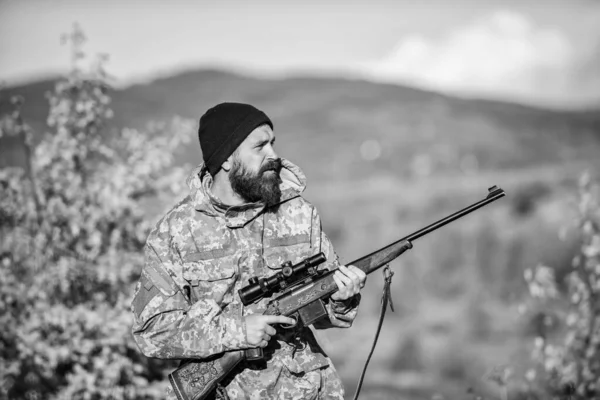 Bearded hunter spend leisure hunting. Focus and concentration of experienced hunter. Hunting and trapping seasons. Hunting masculine hobby. Man brutal gamekeeper nature background. Hunter hold rifle