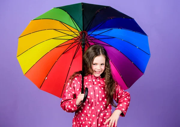 Дощовий день весело. Щаслива прогулянка під парасолькою. Насолоджуйтесь концепцією дощу. Осінній сезон. Дівчинка щаслива тримає барвисту парасольку веселки. Веселка завжди після дощу. Дощова погода з правильним одягом — стокове фото