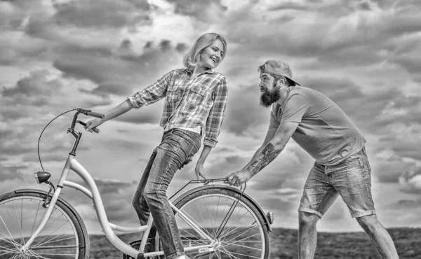 Serwis rowerowy. Serwis i pomoc. Mechanik pomaga utrzymać rower. Usługi wspomagające. Kobieta jedzie rower na tle nieba. Człowiek pomaga utrzymać równowagę jazdy rowerem. Dziewczyna jazda na rowerze, podczas gdy człowiek wspierać ją — Zdjęcie stockowe