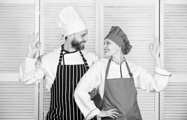 Two smiling chefs in kitchen. couple in love with perfect food. man and woman chef in restaurant. secret ingredient by recipe. cook uniform. Menu planning. culinary cuisine. Family cooking in kitchen