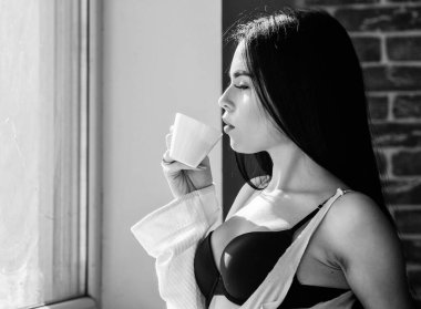 Kız seksi göğüsler pencere kenarında kahve içme. Çekici kadın iç çamaşırı evde rahatlatıcı. Mükemmel kahve zamanı. Ama önce kahve. Huzur ve huzur. Kremsi kapuçino yudumlayın. Sabah ritüeli