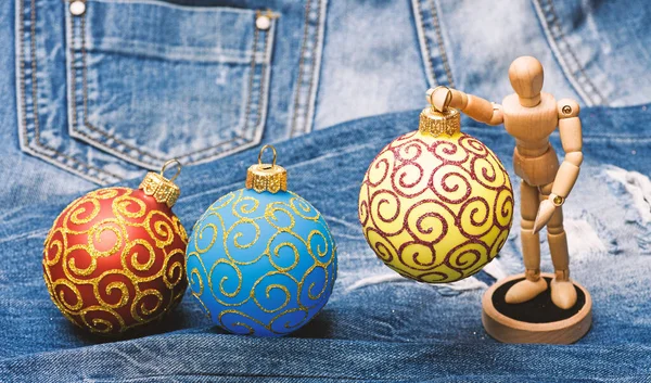 Decorações de Natal em fundo de ganga fechar. Brinquedo de corpo humano de madeira segurar bola de decoração de Natal. Brinquedos decorativos de Natal. Modelo de madeira e ornamentos. Conceito de decorações de Natal — Fotografia de Stock